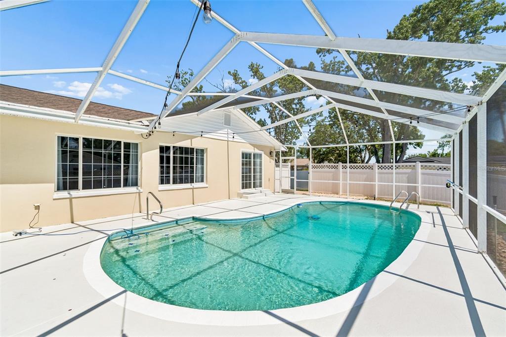 A single-story house with a beige exterior, white garage door, and a concrete driveway — 2959 MAPLE COURT, DUNEDIN, FL