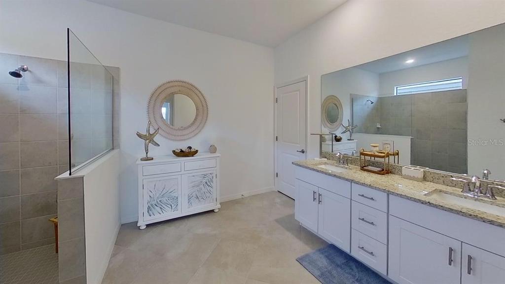 A bathroom features a double vanity, a walk-in shower, and a white cabinet with mirror — 1505 SADDLEWOOD CIRCLE, PORT CHARLOTTE, FL