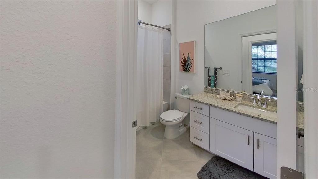 A bathroom features a white vanity with a granite countertop, a toilet, and a shower-tub — 1505 SADDLEWOOD CIRCLE, PORT CHARLOTTE, FL