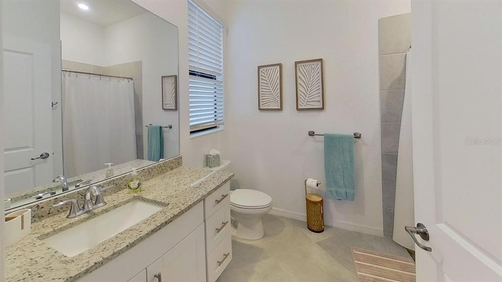 A bathroom features a granite vanity, white cabinets, a toilet, and a tiled shower area — 1505 SADDLEWOOD CIRCLE, PORT CHARLOTTE, FL