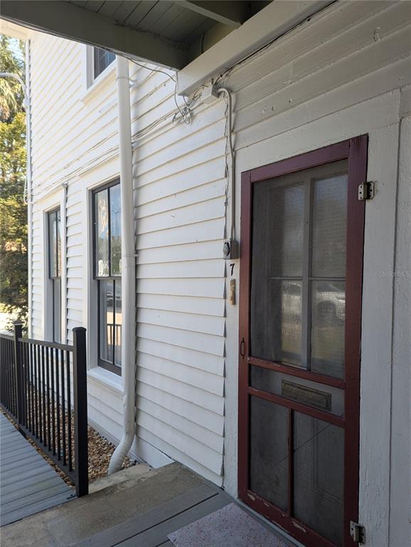 An exterior view of a white-sided building with a red screen door and windows — 6635 SE 221ST STREET UNIT 7, HAWTHORNE, FL