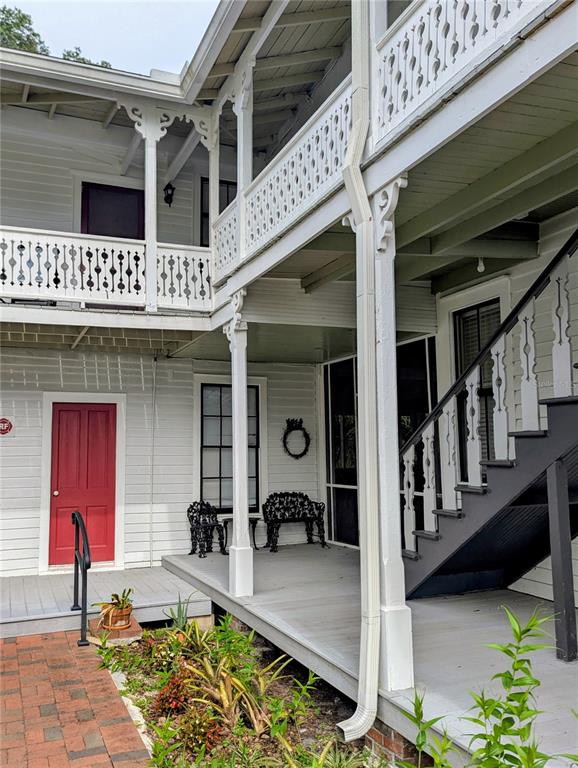 A two-story white house features a wooden porch, decorative railings, and a red door — 6635 SE 221ST STREET UNIT 7, HAWTHORNE, FL