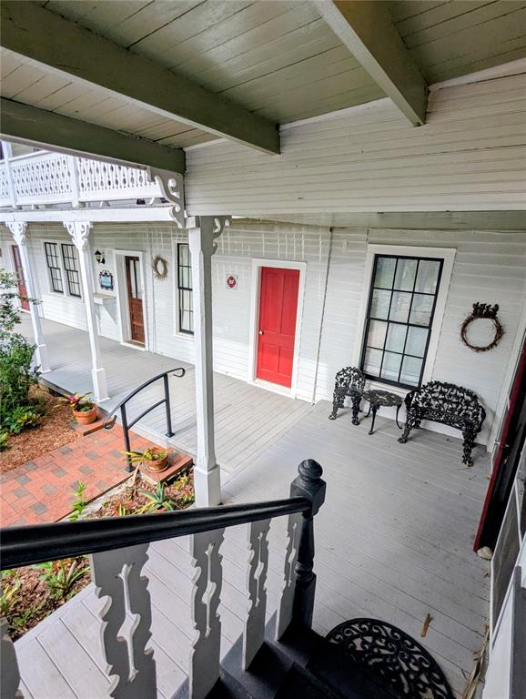 A covered porch features a red door, black metal furniture, and white wooden railings — 6635 SE 221ST STREET UNIT 7, HAWTHORNE, FL