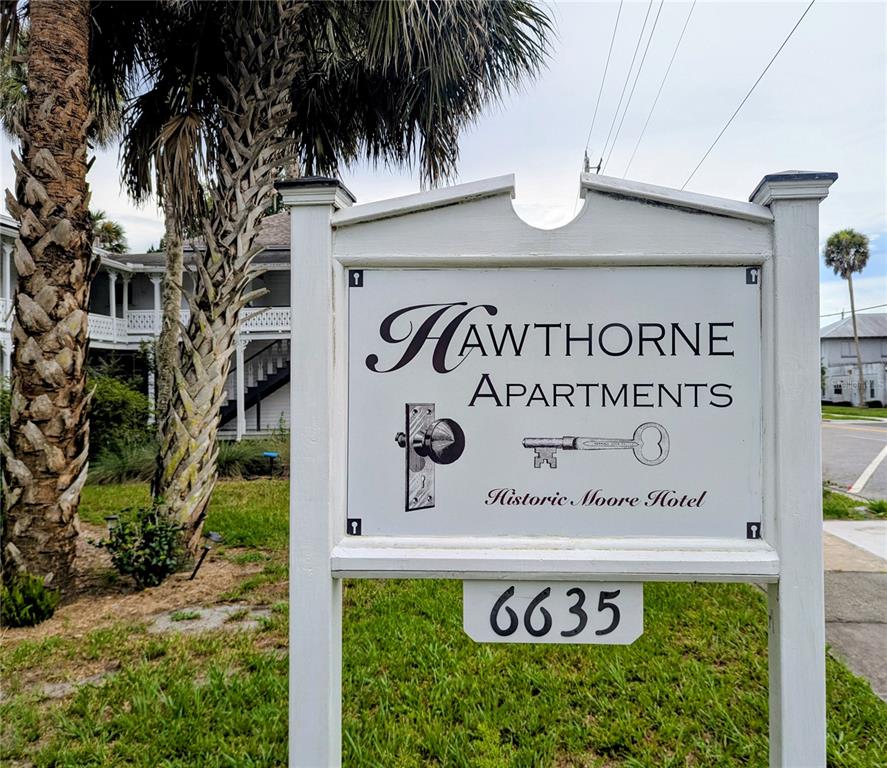 A white sign for Hawthorne Apartments stands in front of a historic building and palm trees — 6635 SE 221ST STREET UNIT 7, HAWTHORNE, FL