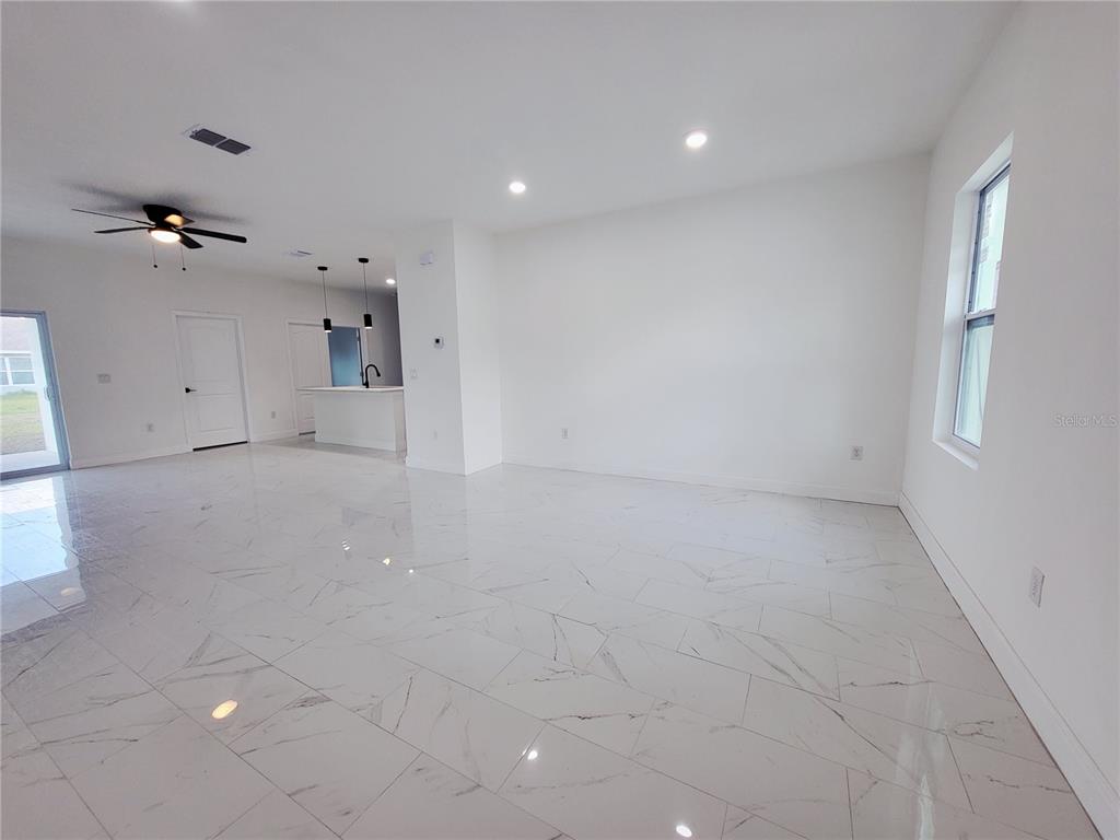 An open-concept living area features white marble-look tile flooring, recessed lighting, and a kitchen island — 1098 HAMMACHER AVENUE SW, PALM BAY, FL