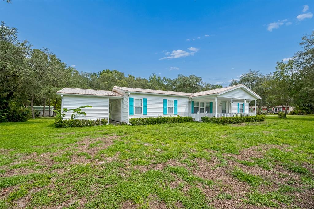 A single-story white manufactured home with teal shutters and a covered front porch — 17430 NW 80TH COURT, FANNING SPRINGS, FL