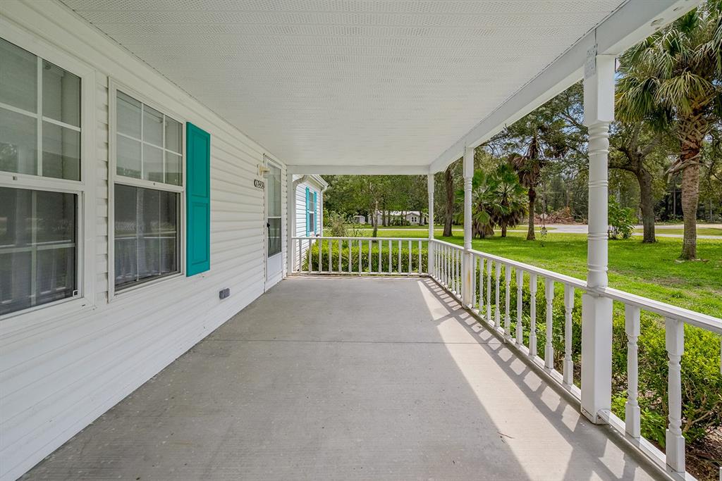 A covered concrete porch with white railings overlooks a grassy yard with trees — 17430 NW 80TH COURT, FANNING SPRINGS, FL
