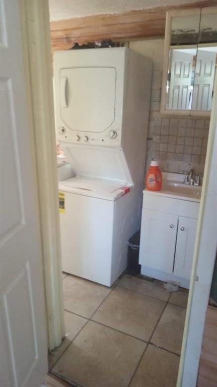 A laundry area features a stacked washer and dryer unit next to a small vanity sink — 6631 ROSATI LANE S, ST PETERSBURG, FL