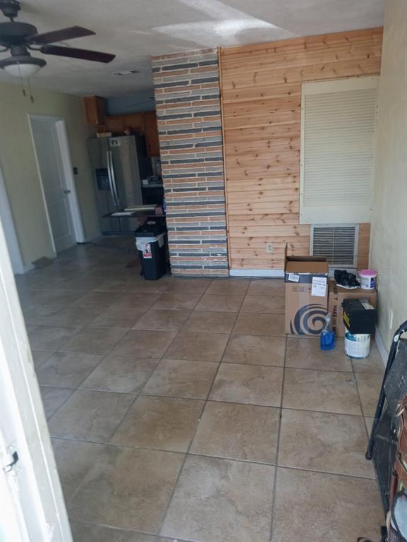 A room with tan tile flooring, a wood-paneled wall, and a stone-accented pillar — 6631 ROSATI LANE S, ST PETERSBURG, FL