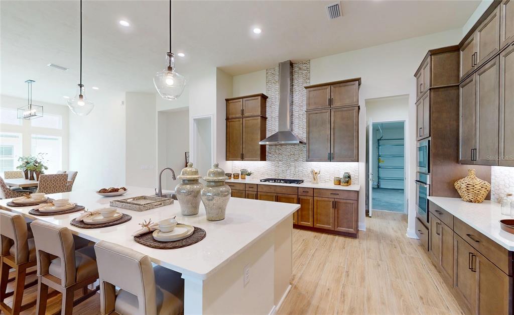 A modern kitchen features a large white island, wooden cabinets, and stainless steel appliances — 3491 SW 111TH DRIVE, GAINESVILLE, FL