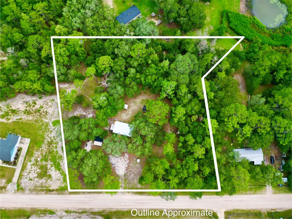 An aerial view shows a wooded residential lot with a house and outbuildings outlined in white — 107 CRYSTAL LAKE DRIVE, MELROSE, FL