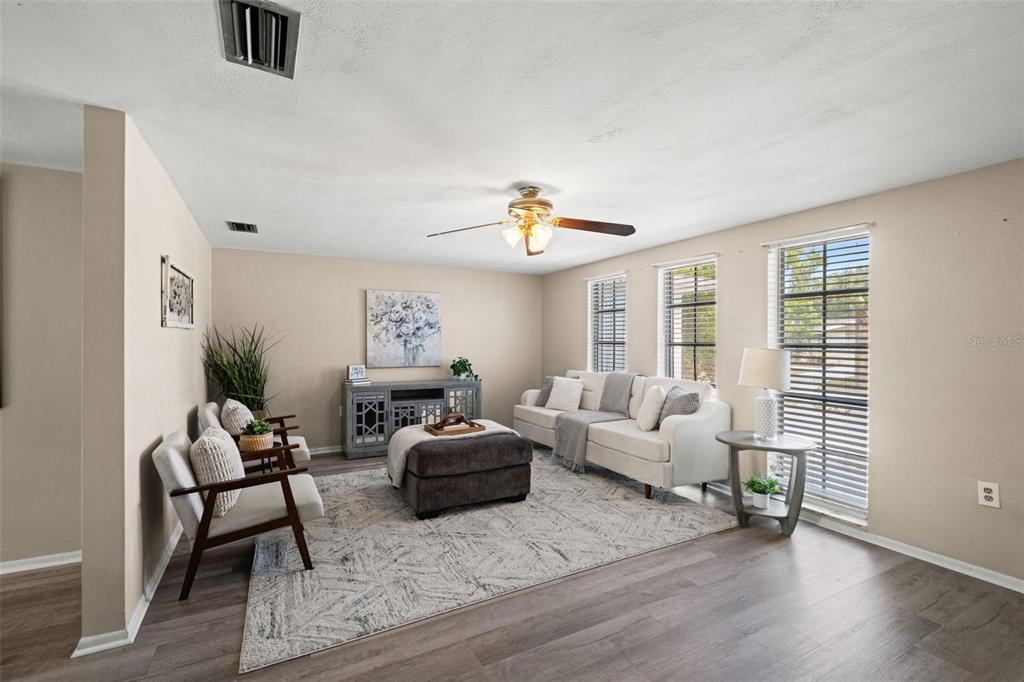 A living room features a brown sectional sofa, a wooden coffee table, and three windows — 7710 BIRCHWOOD DRIVE, PORT RICHEY, FL