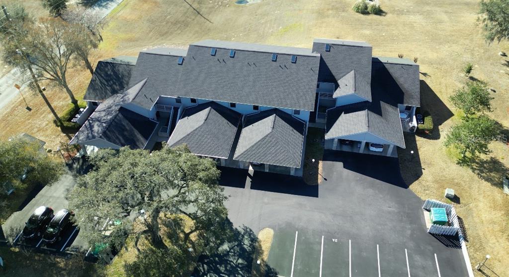 An aerial view shows a multi-unit residential building with a dark shingled roof and parking — 810 E GILCHRIST COURT UNIT 3B, HERNANDO, FL