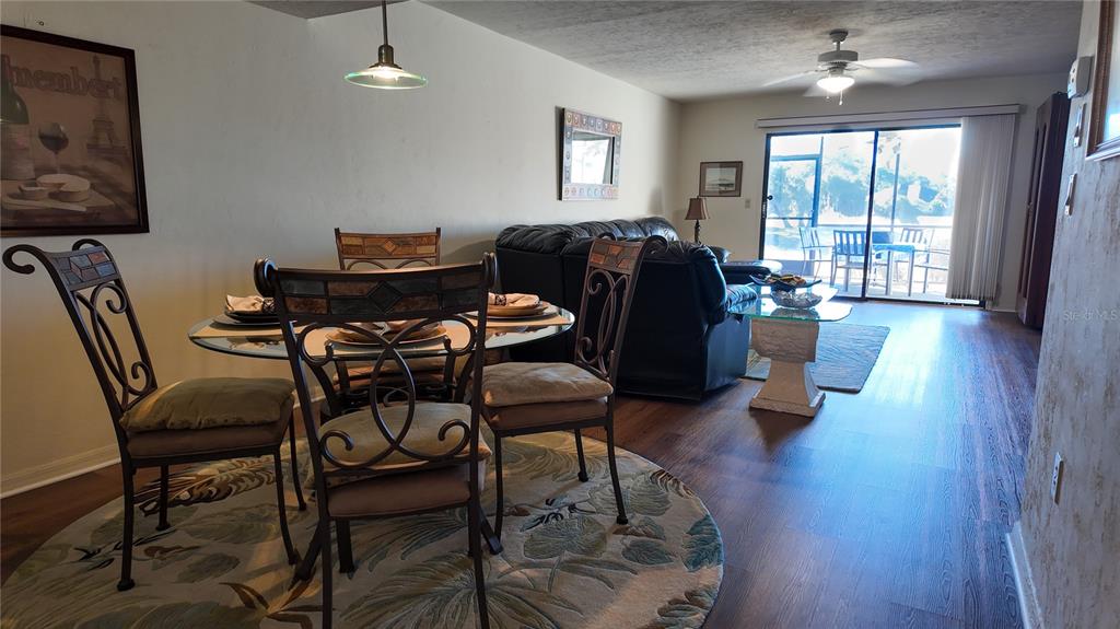 A dining area with a glass table and chairs sits before a living room — 810 E GILCHRIST COURT UNIT 3B, HERNANDO, FL