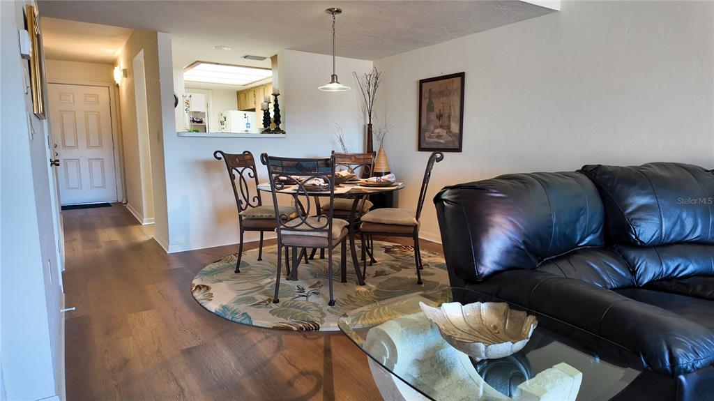 A dining area with a round table and chairs sits adjacent to a living room — 810 E GILCHRIST COURT UNIT 3B, HERNANDO, FL