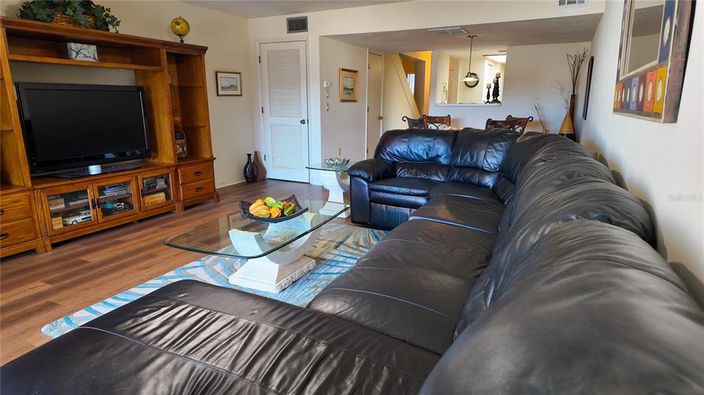A living room features a large black leather sectional, a glass coffee table, and wood cabinetry — 810 E GILCHRIST COURT UNIT 3B, HERNANDO, FL