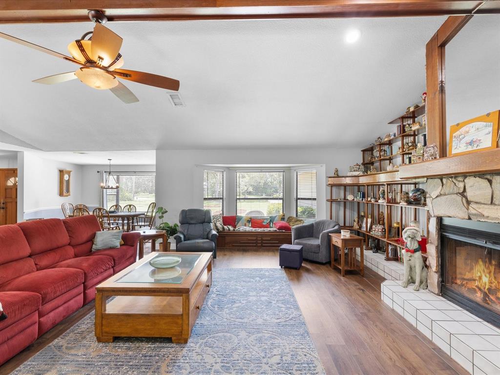 A living room features a red sofa, a stone fireplace, built-in shelving, and a bay window — 6655 MILLSTONE DRIVE, NEW PORT RICHEY, FL