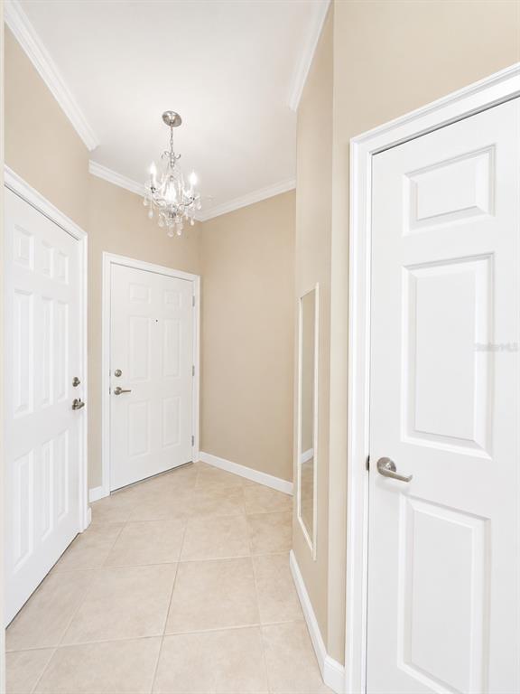 An entryway features beige walls, tile flooring, a crystal chandelier, and three white paneled doors — 351 VANGUARD POINT, CASSELBERRY, FL