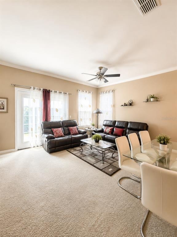 A living room features beige carpet, two dark leather sofas, and a glass dining table — 351 VANGUARD POINT, CASSELBERRY, FL