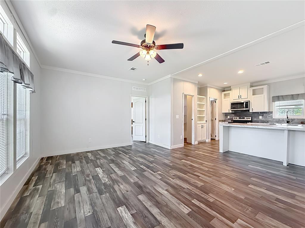 An open-concept living area features wood-look flooring, a ceiling fan, and an adjacent kitchen — 5360 W CARAWAY PLACE, LECANTO, FL