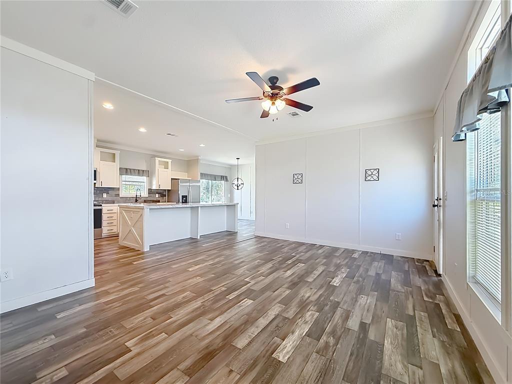 An open-concept living room with wood-look flooring flows into a kitchen featuring a white island — 5360 W CARAWAY PLACE, LECANTO, FL