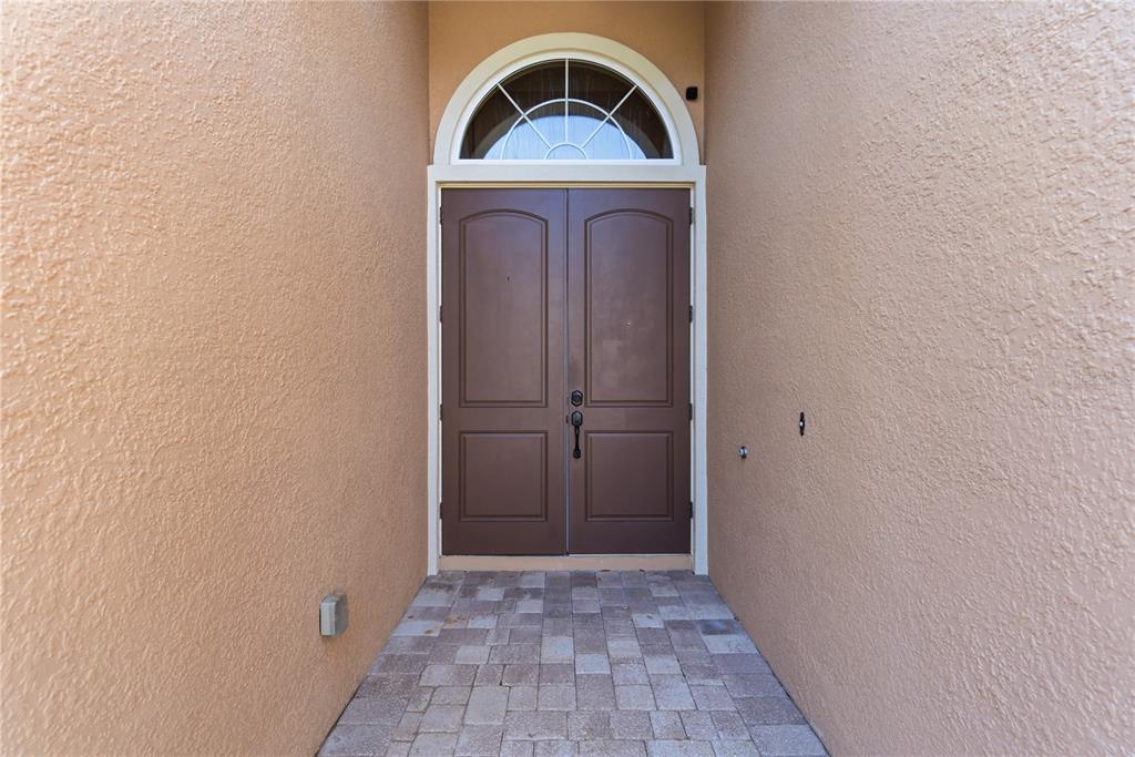 An empty dining room features a chandelier, crown molding, and light-colored stone tile flooring — 8875 SW 73RD LANE, GAINESVILLE, FL