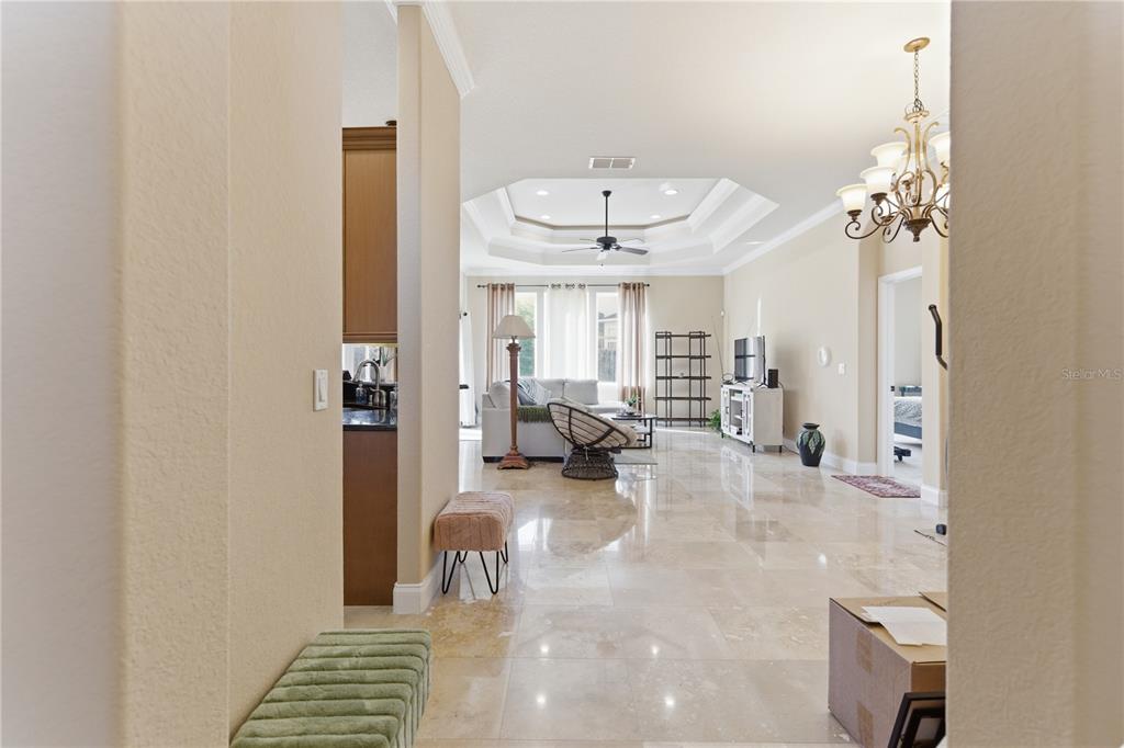 A spacious living room features a tray ceiling, tile flooring, and a view of the backyard — 8875 SW 73RD LANE, GAINESVILLE, FL