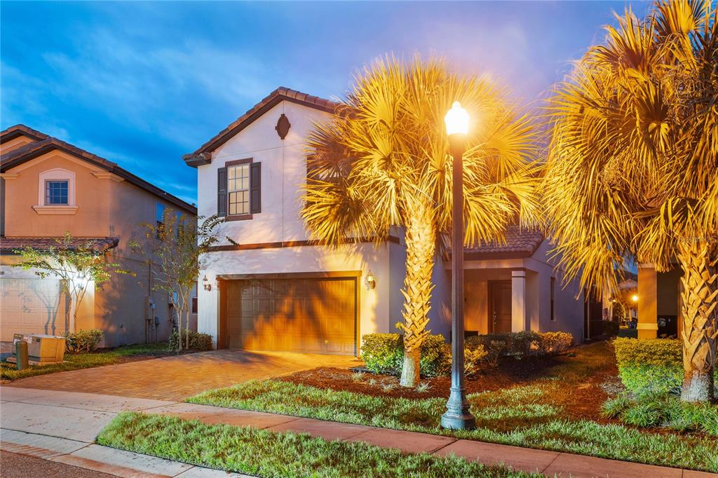 A two-story suburban house with a garage, palm trees, and a street lamp at dusk — 5505 MISTY OAK CIRCLE, DAVENPORT, FL