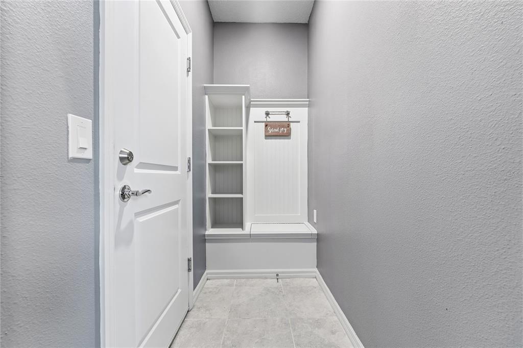 A mudroom area features a white built-in bench with shelving against gray walls — 5505 MISTY OAK CIRCLE, DAVENPORT, FL