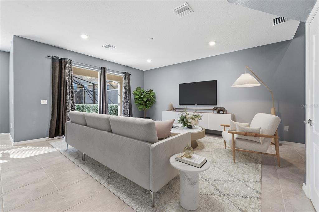 A living room features a grey sofa, a white armchair, and a television on a console — 5505 MISTY OAK CIRCLE, DAVENPORT, FL