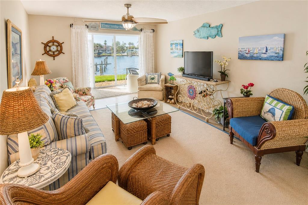 A sunroom with tile floors overlooks a canal with docked boats through large screen windows — 1351 BAYSHORE DRIVE UNIT 108, FORT PIERCE, FL