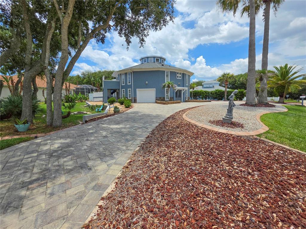 A blue two-story house sits behind a large green lawn with mature trees — 87 BUSCHMAN DRIVE, PONCE INLET, FL
