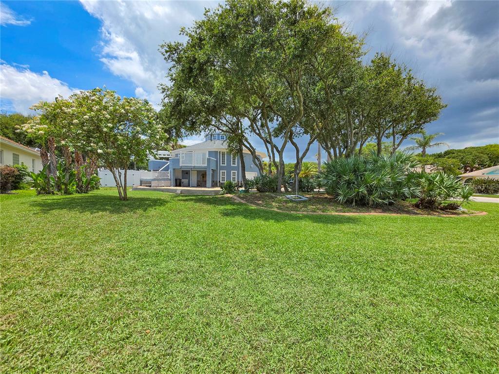 A two-story blue circular house features a paved driveway and palm trees in the yard — 87 BUSCHMAN DRIVE, PONCE INLET, FL