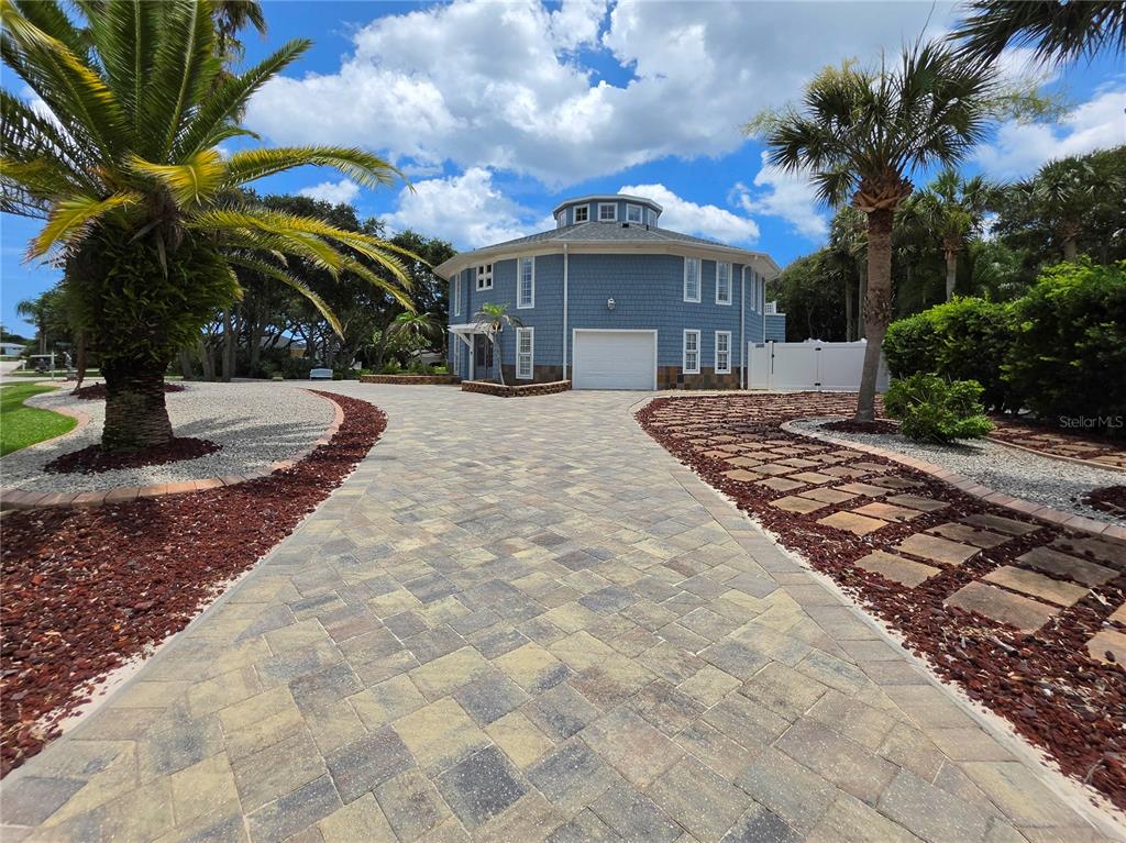 A large green lawn features a landscaped garden bed with trees and shrubs before houses — 87 BUSCHMAN DRIVE, PONCE INLET, FL