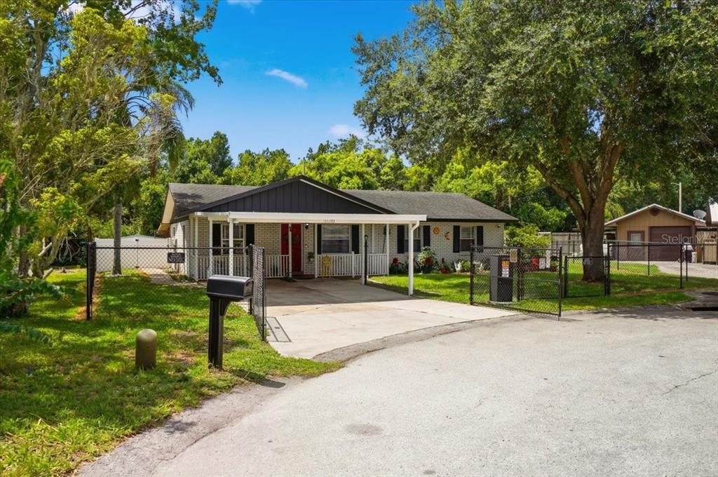 A single-story house with a white brick exterior, a carport, and a chain-link fence — 156 MANSEAU DRIVE, WINTER HAVEN, FL
