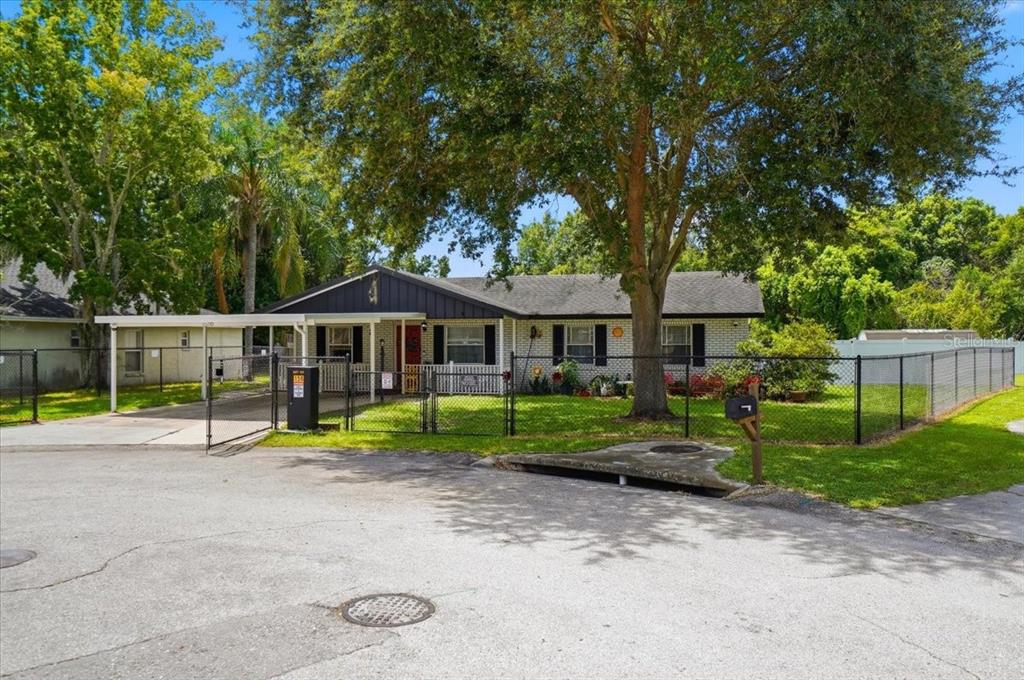 A single-story house with a carport, fenced yard, and large tree in the front — 156 MANSEAU DRIVE, WINTER HAVEN, FL