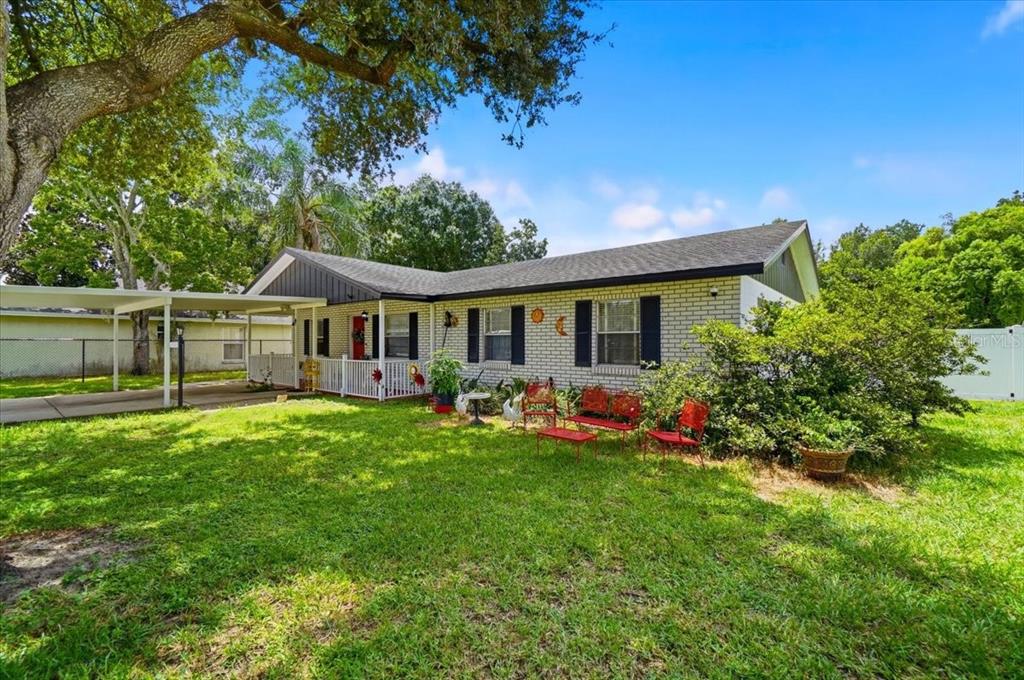 A single-story brick house with a carport, front porch, and a grassy yard — 156 MANSEAU DRIVE, WINTER HAVEN, FL