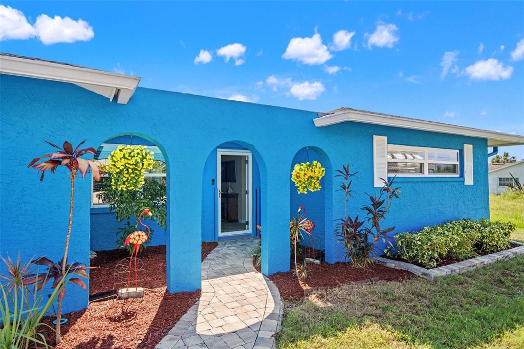 A bright blue house exterior features arched entryways, a stone walkway, and a front garden — 4114 ORCHID DRIVE, HERNANDO BEACH, FL