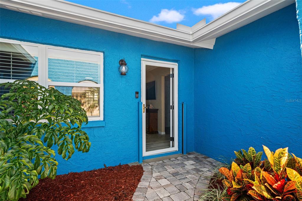 A bright blue exterior wall features a glass storm door and a large window — 4114 ORCHID DRIVE, HERNANDO BEACH, FL