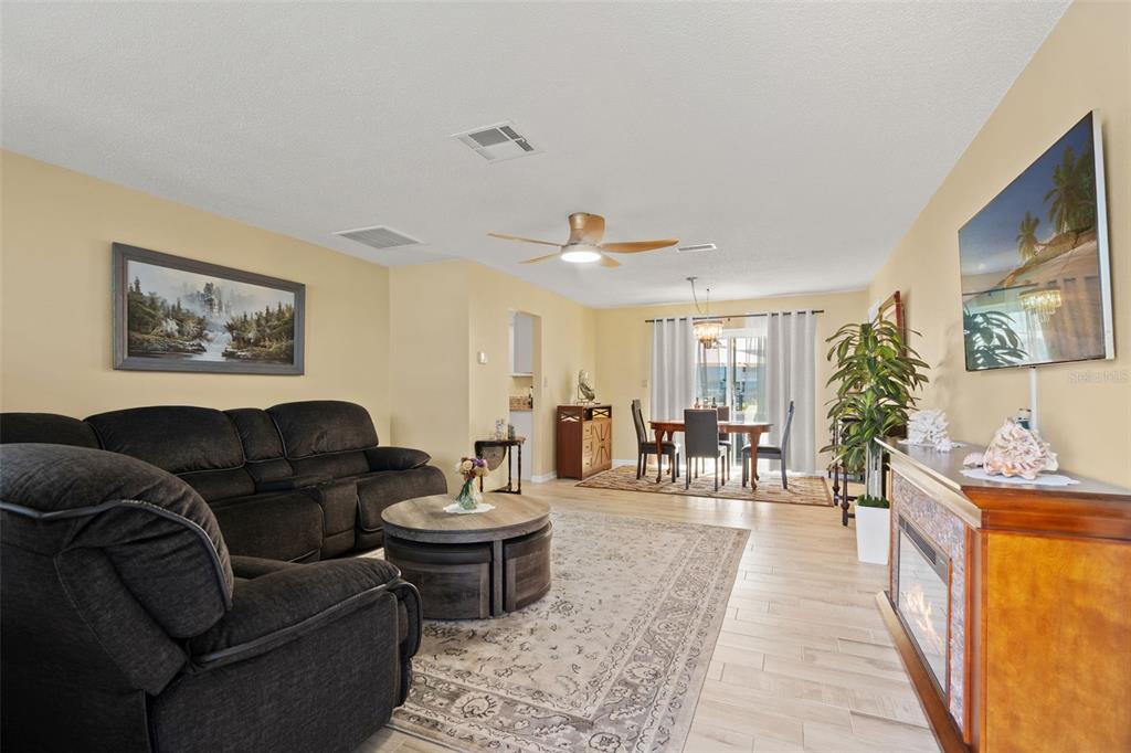 A living room with a dark sofa, round coffee table, fireplace, and adjacent dining area — 4114 ORCHID DRIVE, HERNANDO BEACH, FL