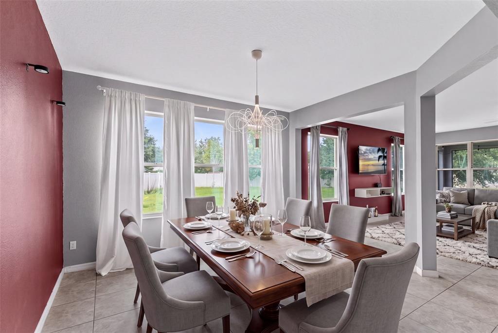 A dining room features a wooden table, gray upholstered chairs, and red accent walls — 1553 PINE MARSH LOOP, ST CLOUD, FL