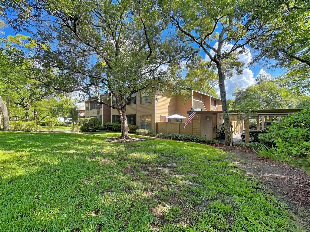 A brown shed with a covered patio area sits on a paved stone courtyard — 1006 LENNOX ROAD W UNIT 1006, PALM HARBOR, FL