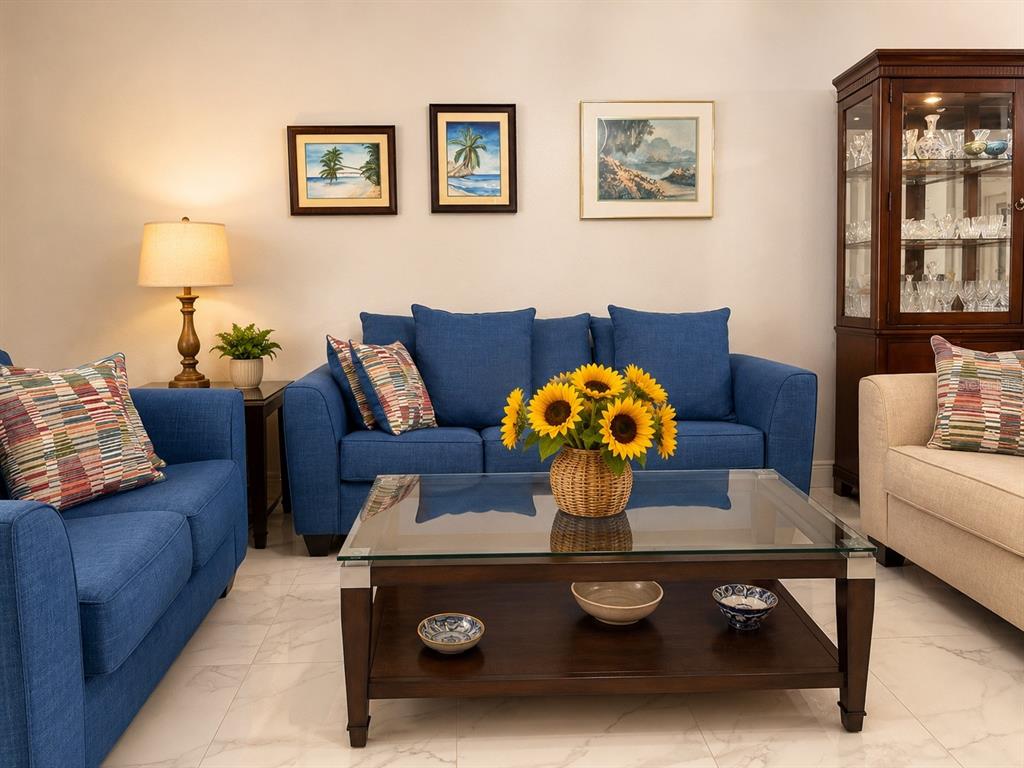 A living room features blue sofas, a glass-topped coffee table, and artwork on the wall — 9416 MYRTLE CREEK LANE UNIT 702, ORLANDO, FL