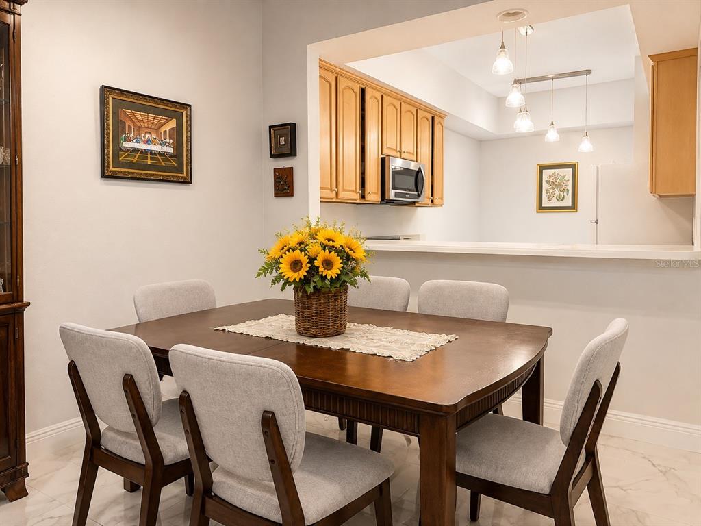 A dining room with a wooden table, six chairs, and a pass-through to the kitchen — 9416 MYRTLE CREEK LANE UNIT 702, ORLANDO, FL
