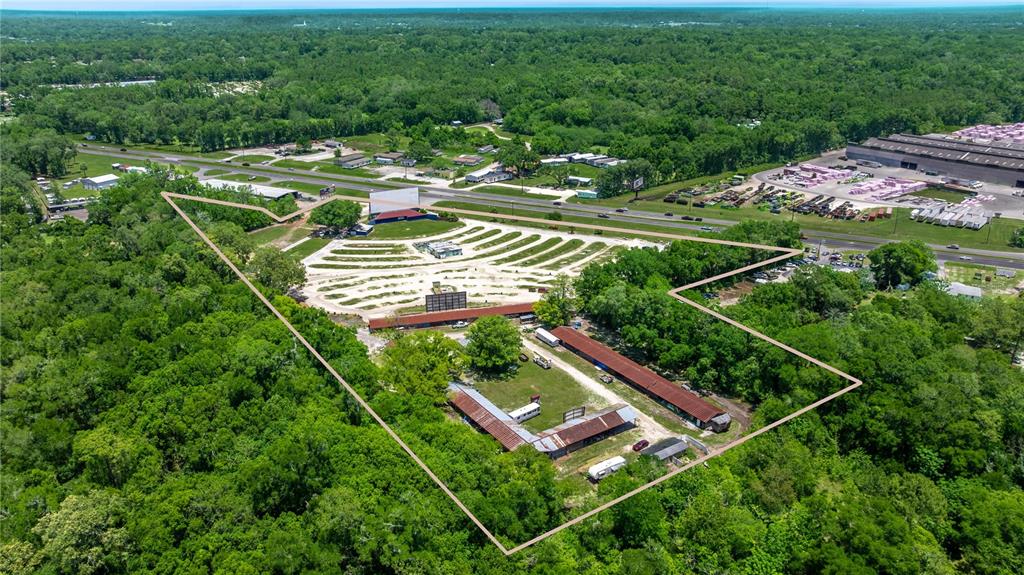 An aerial view shows a drive-in theater and adjacent motel buildings surrounded by dense forest — 4850 S PINE AVENUE, OCALA, FL