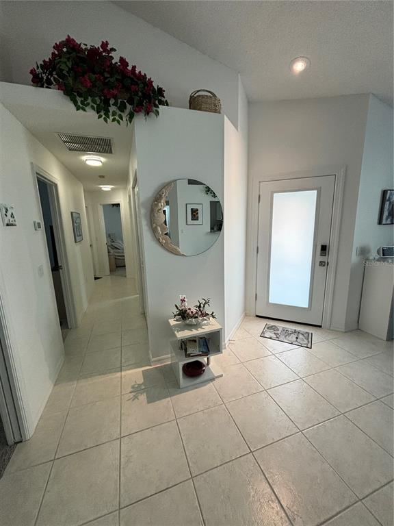 An entryway features tiled floors, a circular mirror, a small side table, and a front door — 1332 CAPRI ISLES BOULEVARD, VENICE, FL