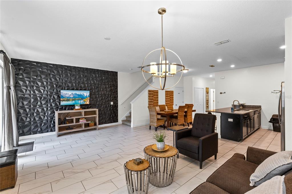 An open-concept living and dining area features a textured black accent wall and tile flooring — 3087 JULIET DRIVE, KISSIMMEE, FL