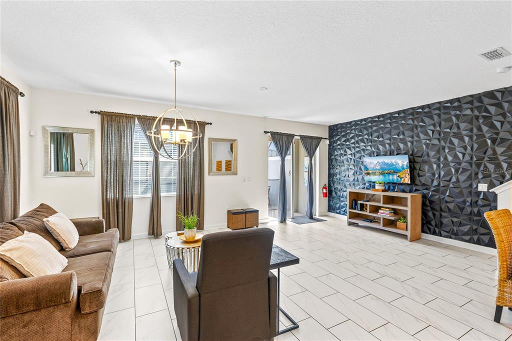 A living room features a dark geometric accent wall, tile flooring, and a brown sofa — 3087 JULIET DRIVE, KISSIMMEE, FL