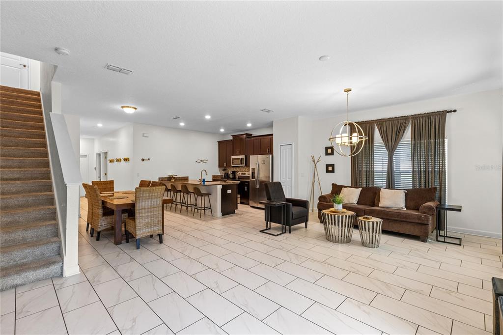 An open-concept living area features a kitchen with dark cabinets, a dining set, and stairs — 3087 JULIET DRIVE, KISSIMMEE, FL