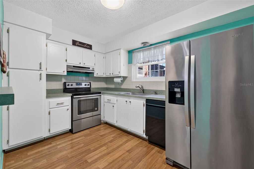 A kitchen with white cabinets, stainless steel appliances, a green countertop, and wood-look flooring — 3585 41ST TERRACE S UNIT 225, ST PETERSBURG, FL